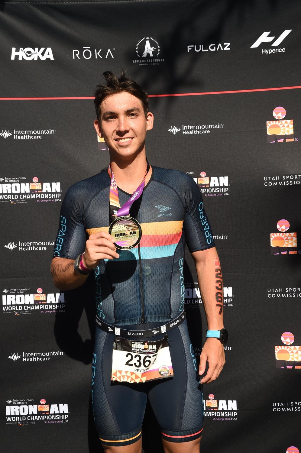 Peyton Thompson holds up his medal for winning fourth place at the 2021 Ironman World Championship in St. George, Utah.